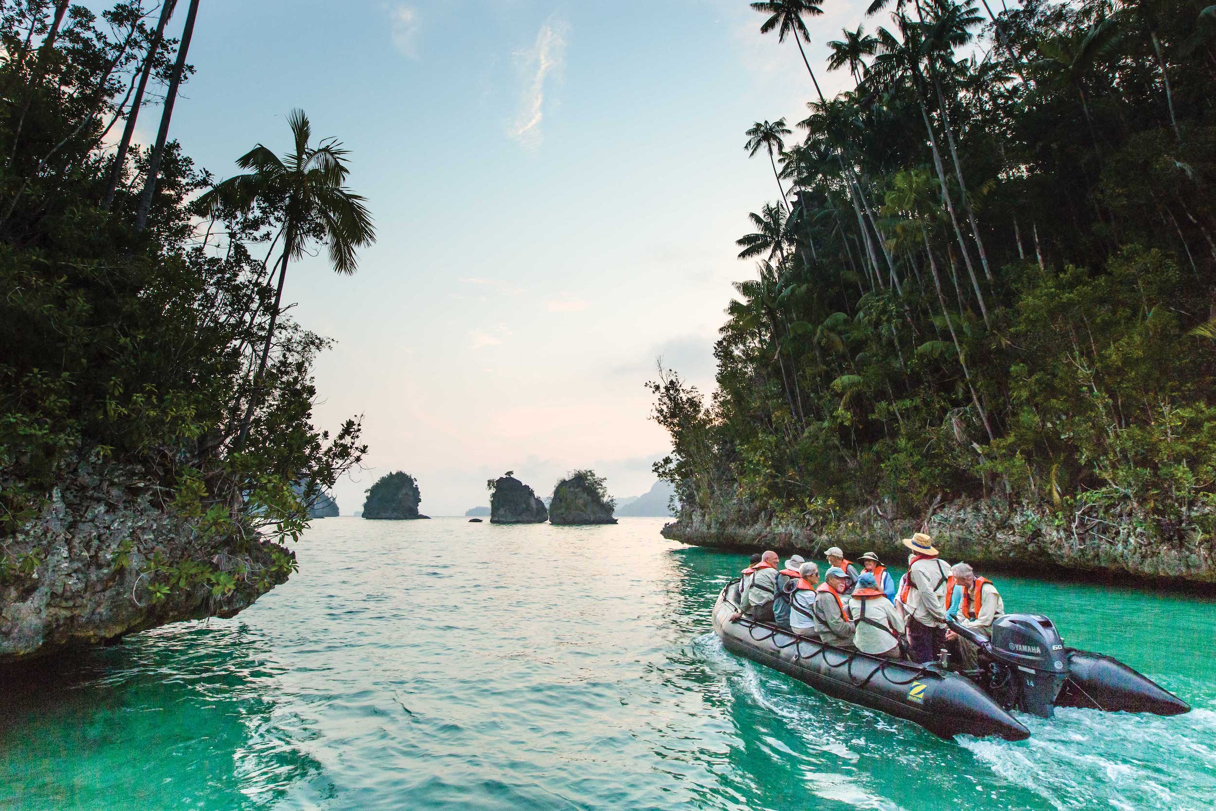 A Zodiac boat cruises through the emerald green waters of Indonesia
